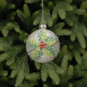 A Metallic, crackle glass bauble with holly design hanging from a pine tree.