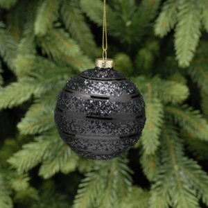 A black glitter, glass bauble with a stripey design hanging from a pine tree.