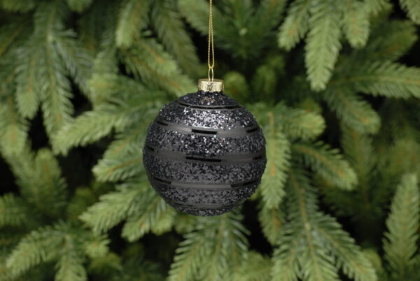 A black glitter, glass bauble with a stripey design hanging from a pine tree.