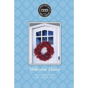 A Welcome Home Large scented sachet. An image of a white door with a red wreath on it sits against a sky blue background. Beneath the image in white the text reads 'BRIDGEWATER CANDLE COMPANY Welcome Home SCENTED SACHET'.