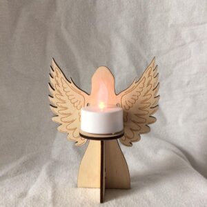 A 3D laser cut wooden angel with open wings tea light holder shown with lit battery operated white tea light candle.