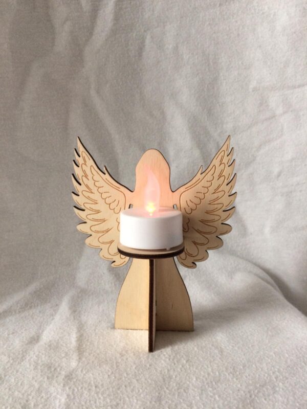 A 3D laser cut wooden angel with open wings tea light holder shown with lit battery operated white tea light candle.