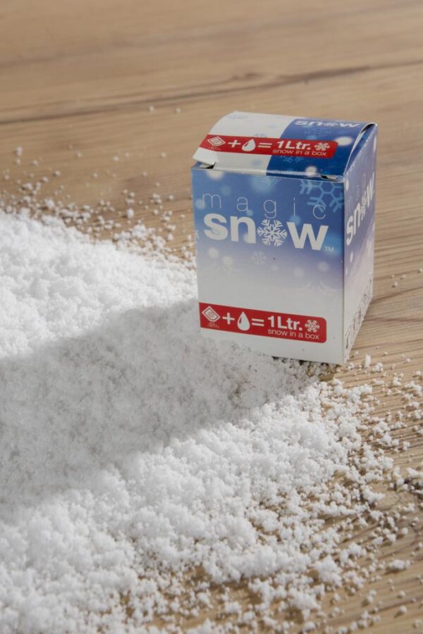 A box of fake snow is sitting on a wooden table.