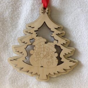 A 3D laser cut wooden Christmas tree hanging decoration with a couple of cute snowmen holding hearts in the middle hanging on a red ribbon.