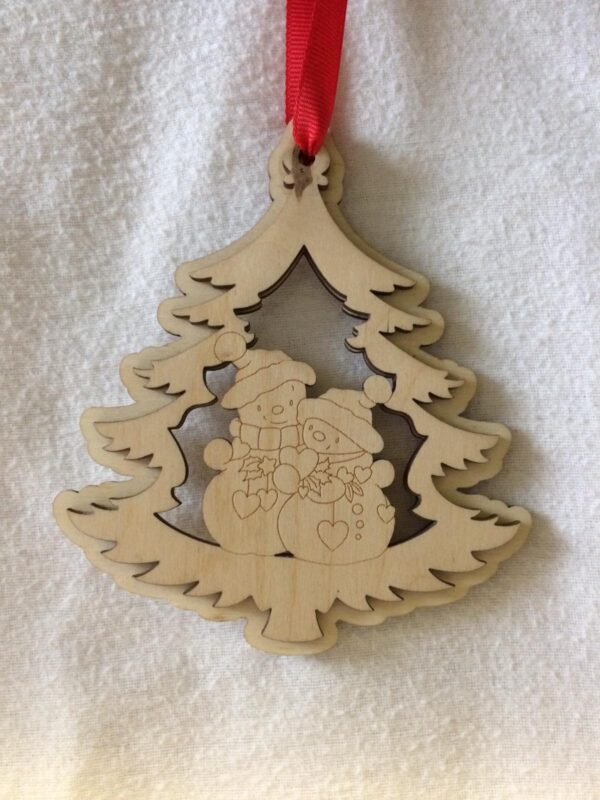 A 3D laser cut wooden Christmas tree hanging decoration with a couple of cute snowmen holding hearts in the middle hanging on a red ribbon.