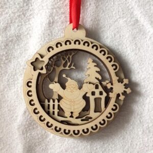 A round decorative 3D laser cut wooden tree hanging decoration with a cheerful Santa Claus in a festive scene in the middle hanging on a red ribbon.