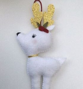 A handmade white felt reindeer ornament with sparkly gold antlers and collar with holly decoration.