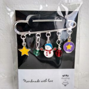 A Festive Brooch, made from a silver kiltpin with festive charms including a yellow star, a green faceted bead, a cute snowman with a blue hat and red scarf, a red faceted bead and a pruple bauble with yellow star. Hand made with love by Bunting & Beads.