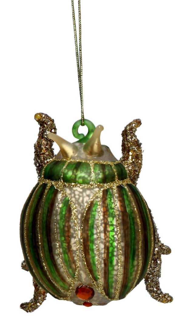 A blown glass, in antique gold, beetle tree decoration. It has a round body with green and brown vertical stripes across its back and neck with gold glitter detail and red diamante spots at the base. It hangs from a gold strings.