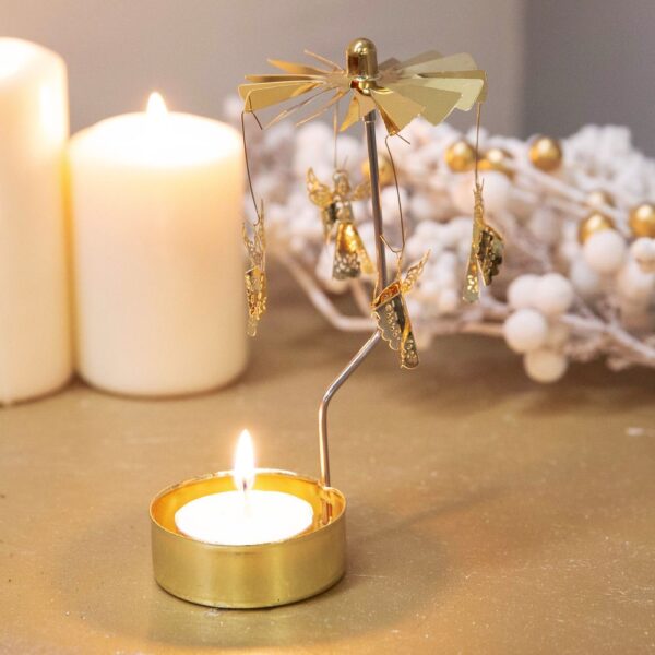 A Gold Angel, rotary tealight holder, next to a candle.