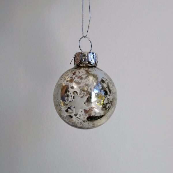 A miniture clear glass Christmas tree bauble decorated in an antique mirror style with white stars around it.