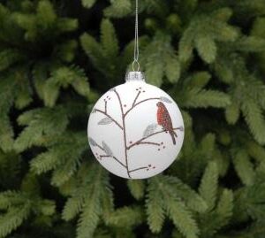 A matt white glass Christmas tree bauble decorated with a festive brown tree with silver leaves and red berries, nestled in the brancjes is a red brested robin. All the details are made from sparkly glitter.