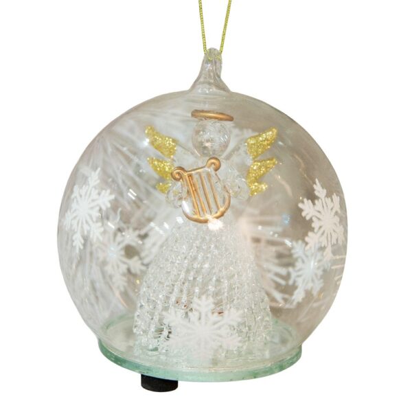 A clear glass dome with white snowflakes around the outsides hangs from a gold thread. Inside the dome is a handmade glass angel wth a delicate lattice skirt and gold glitter tipped wings. She is holding a matt gold glass harp which matches her halo. On the bottom of the dome you can see the swith that operates the LED lights inside.