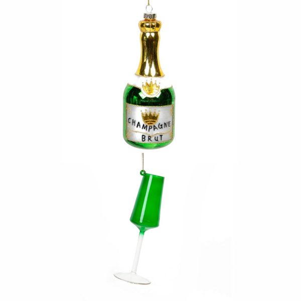 A small glass Christmas tree decoration in the shape of a green Champagne bottle decorated with metallic gold on its neck with a white pearlised label with a gold crwon and black text that reads 'Champagne Brut', hanging from the bottom of the bottle is a green fluted champage glass with a clear stem.