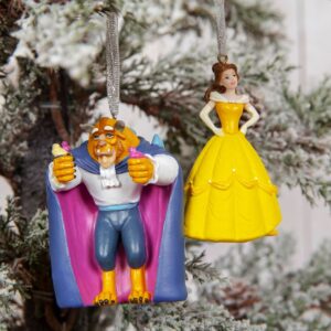 Disney's 'Beauty' and 'Beast' Hanging Tree Decoration christmas ornaments. Beast on the left wear his trademark cape and beastly appearance. In his hands he holds a variety of small birds, a bluebird is perched on his shoulder. Belle is wearing her trademark yellow ballgown. Both are hanging from silver glitter ribbons.