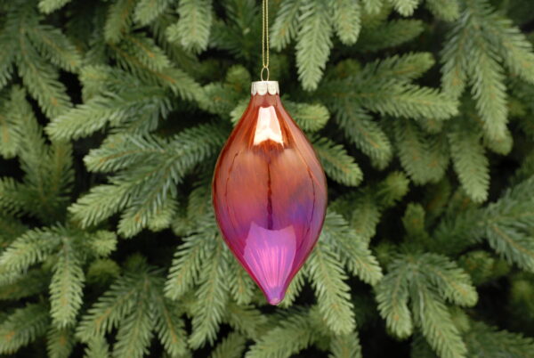 A red and pink ombre coloured, teardrop shaped glass Christmas tree bauble with a twist hanging from a gold string.