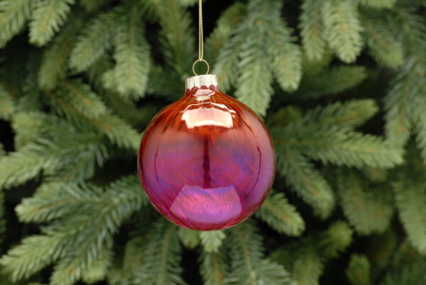 A red and pink ombre coloured, round glass Christmas tree bauble with a twist hanging from a gold string.