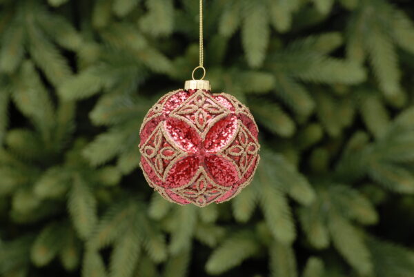 A moulded glass Christmas bauble with an embossed flower pattern. Covered in red glitter and featuring matt gold bead detail in a diamond pattern. Hanging from a gold thread.