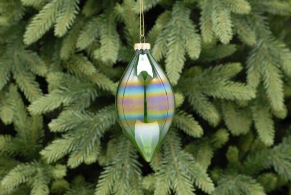 A translucent green iridescent olive drop shaped Christmas tree bauble hanging from a fir tree.