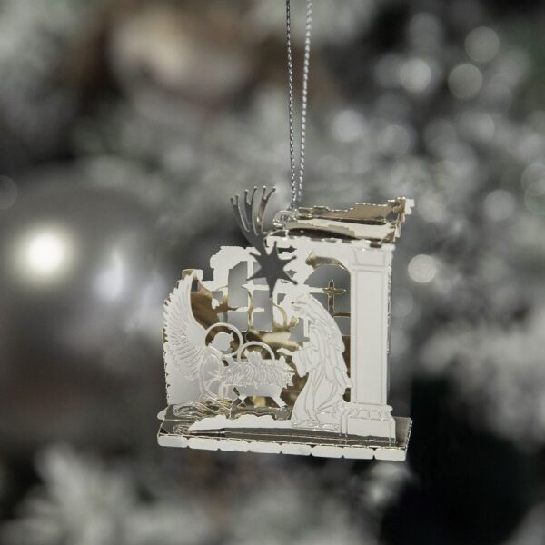 A 3D die-cut laser etched gold metal Nativity Christmas tree decoration featuring Mary and the Angel Gabrielkneeling in the stable looking into the manger at the baby Jesus with a shooting star above them. hnaging from a silver thread.