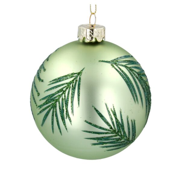 A matt, pale green, glass Christmas tree bauble decorated with dark green palm leaves with green glitter detail on them.