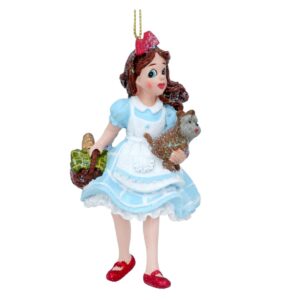 A polyresin figurine Chrsitmas tree decoration depicting Dorothy from the Wizard of Oz. Dorothy is wearing a blue dress with white petticoats and matching apron. On her feet she has the ruby red slippers which have been finished with red glitter. He long brown hair hangs down ove r her shoulders and she wears a matching red glitter bow in her hair. In her right hand she carryws a brown wicker picnic basket covered with a green and yellow check cloth, there is a small loaf of bread poking out the back. In her left arm she carries Toto her small brown terrier dog.