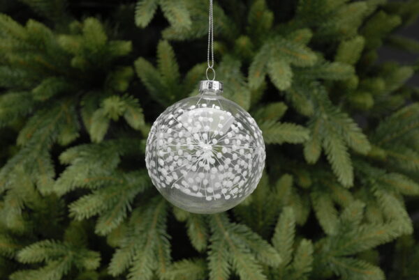 A round, clear glass Christmas tree bauble decorated with white starbursts all around it, hanging from a silver string.