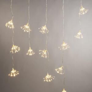 A lit set of Warm White Starburst Light Curtain lights hanging in front of a grey wall.