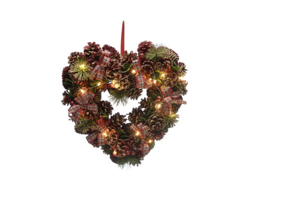 A Heart-Shaped Christmas Wreath decorated with natural pine cones with iridescent glitter frosting, Faux pine tree sprigs and red, white and green tartan ribbon bows. Warm white LED lights are interwoven through the wreath. It hangs from a red ribbon.