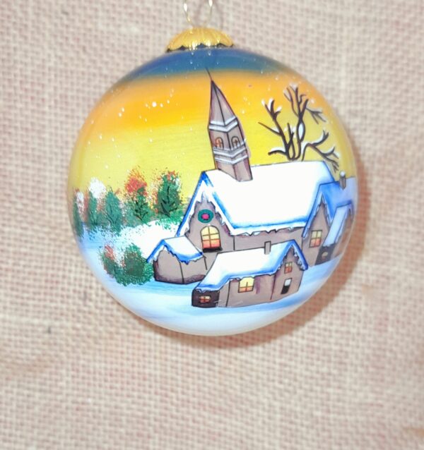 A Beautiful Hand Painted Bauble with a Snowy Church Scene set against a golden sky.