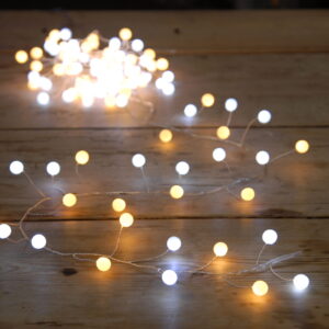 120 White and Warm LED Glow Ball Lights on a wooden table.