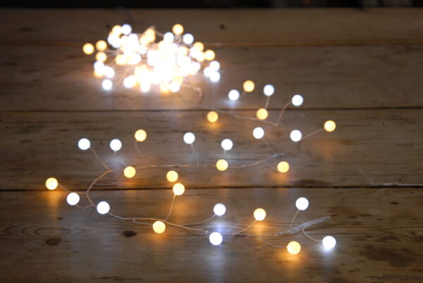 120 White and Warm LED Glow Ball Lights on a wooden table.