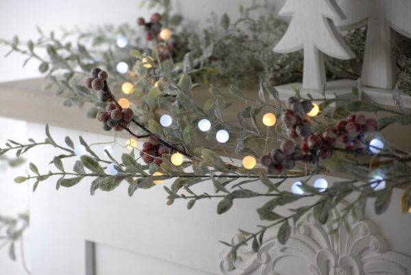 A mantle with 120 White and Warm LED Glow Ball Lights and berries.