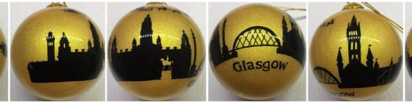 Beautiful handpainted glass Christmas tree bauble with the Glasgow Skyline in black against a gold glitter background. Santa in his sleigh being pulled by reindeer flys overhead and the text at the bottom reads 'Glasgow'.