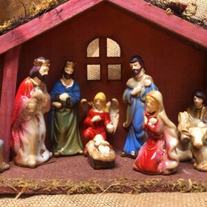 A Wooden Stable Nativity Ornament with Ceramic Pieces depicting Mary, Joseph, Jesus, The Wise Men, The Arch Angel Gabriel and a donkey and a cow.