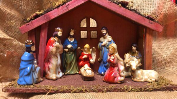 A Wooden Stable Nativity Ornament with Ceramic Pieces depicting Mary, Joseph, Jesus, The Wise Men, The Arch Angel Gabriel and a donkey and a cow.