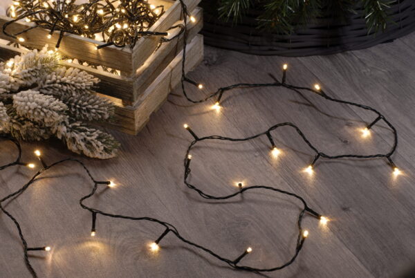 200 Warm White Fairy Lights on a wooden floor next to a christmas tree.