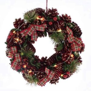 A round Christmas Wreath decorated with natural pine cones dyed red with iridescent glitter frosting, Faux pine tree sprigs and red, white and green tartan ribbon bows. Warm white LED lights are interwoven through the wreath. It hangs from a red ribbon.