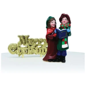 A polyresin Victorian Carol Singers shaped cake decoration. The two carollers are dressed for winter in hats, scarves and coats. Between them they are holding a blue book from which they sing. Their faces depict that they are singing. They are stood next to a gold plastic Merry Christmas motto cake decoration.