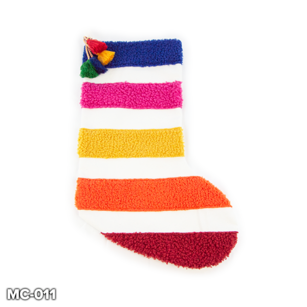 A plain white stocking with 5 horizontal bands of boucle coloured fabric, starting at the top with navy, pink, yellow, orange and red and alternating with the white stripes of the stocking. At the top there is a collection of colourful tassels on gold cord in red, yellow, blue and green.