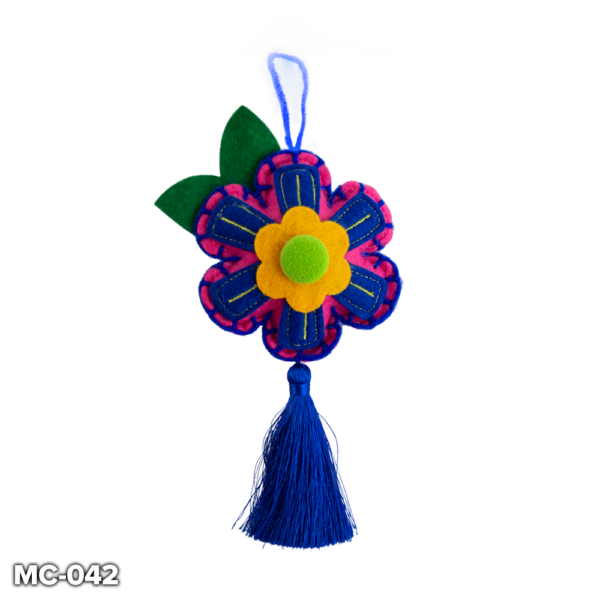 A pink felt, flower shaped Christmas tree decoration. This pink felt flower has a blue and yellow petals with a yellow and green centre. It has blue stitching around the outside. At the top there is a loop of blue wool for hanging and two green felt leaves. A blue tassle hangs from the bottom petal of the flower.