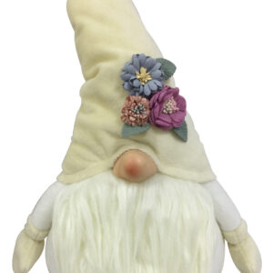 A cream coloured Christmas Gonk with flowers. The body of this gonk is white with cream coloured mittens at the end of each arm. It has a fluffy cream coloured beard which sits beneath its pink nose. On it's head it has a pointy cream hat that has a small posy of blue, purple and pink flowers with green leaves that sits above the nose on the left hand side.