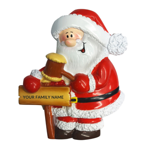 A polyresin Personalisable Christmas tree decoration in the shape of Santa. Santa is hammering a signpost with a mallet. On the signpost there is text that reads 'YOUR FAMILY NAME' implying the decoration can be personalised.