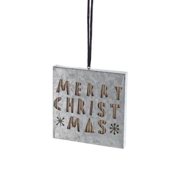 A square, silver metal Christmas tree decoration with the words 'MERRY CHRISTMAS' and two snowflake designs cut out of the metal and backed by corrugated cardboard. Hanging from a black string.