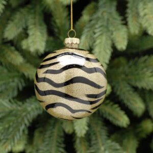 A clear glass bauble decorated with black zebra print on the inside and filled with gold glitter. Hanging from a gold string.