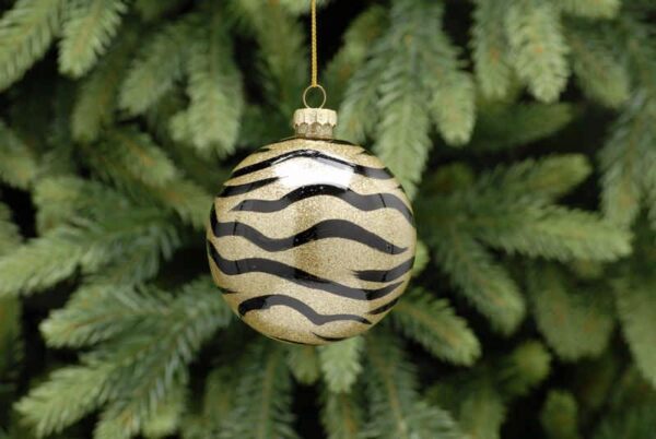 A clear glass bauble decorated with black zebra print on the inside and filled with gold glitter. Hanging from a gold string.