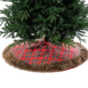 A red tartan fabric Christmas tree skirt with brown fur trim beneath a gren Christmas tree.