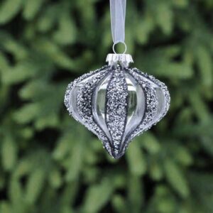 A clear glass, segmented onion shaped Christmas tree bauble with dark grey and silver glitter on every other segment.Hanging from a white ribbon.