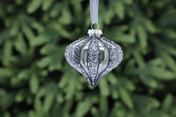 A clear glass, segmented onion shaped Christmas tree bauble with dark grey and silver glitter on every other segment.Hanging from a white ribbon.