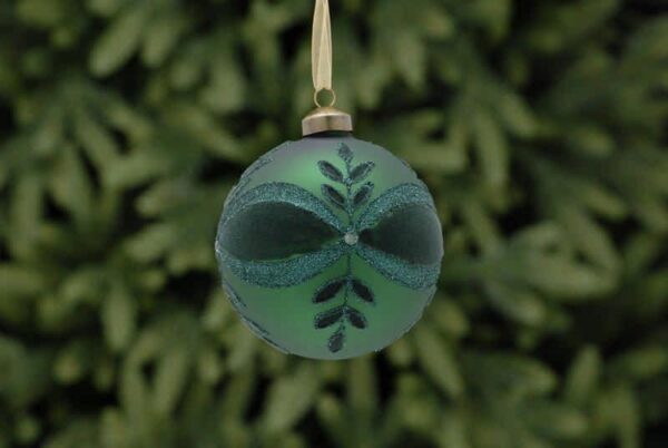 A matt green glass Christmas tree bauble decorated with a leaf and bow pattern in dark green flock and green glitter with a white diamante jewel in the centre.